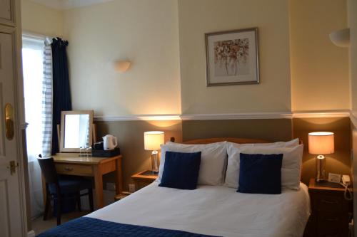 a bedroom with a bed and a desk with a mirror at The Lindum in Hastings