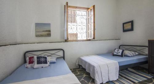 two twin beds in a room with a window at Moorea Country Houses in Petalidhion