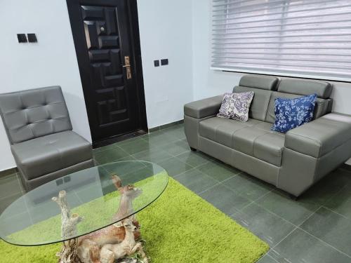 a living room with a couch and a glass table at Caesar's Hotel & Apartment Room #14 in Ikeja