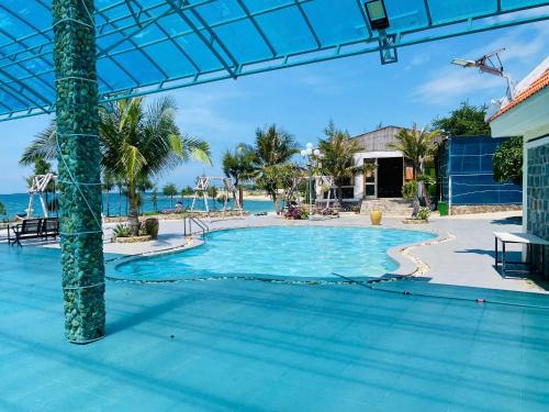 a swimming pool with the ocean in the background at Hòn Cau Resort & Restaurant in Tuy Phong