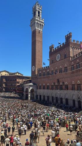 a large crowd of people in front of a building with a clock tower at Casa i servi in Siena