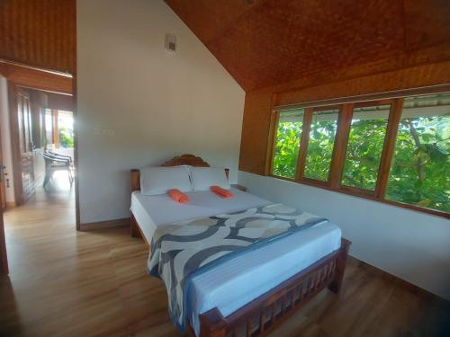 a bedroom with a bed in a room with windows at Sherly Cottages in Varkala