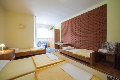 a large living room with a brick wall and beds at Guest House Hodak in Rakovica