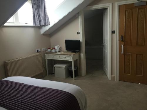 a bedroom with a bed and a desk with a computer at The Clyffe Hotel in Lowestoft