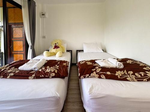 a teddy bear sitting on top of two beds at Nansilarom in Ban Bun Yun