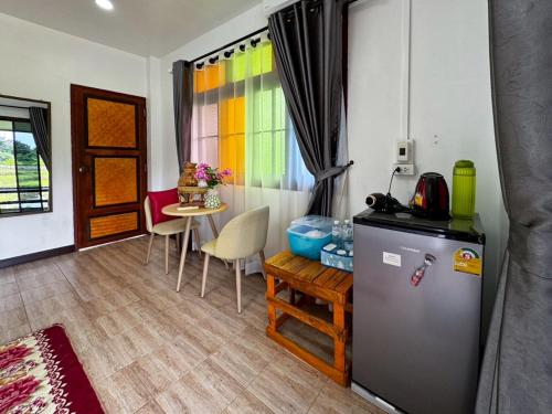 a kitchen with a refrigerator and a table with chairs at Nansilarom in Ban Bun Yun