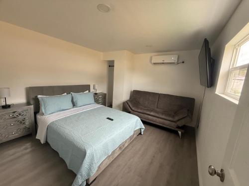 a bedroom with a bed and a couch and a television at Bienes House in Brandon