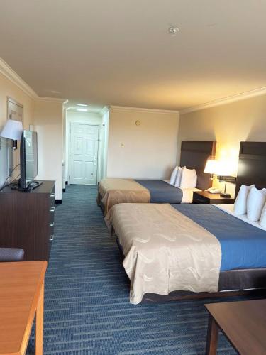 a hotel room with two beds and a flat screen tv at Coratel Inn Ocean Shores Extended Stay in Ocean Shores