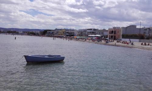 a blue boat in the water next to a beach at Case Vacanza Torre Canne in Torre Canne