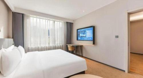 a bedroom with a white bed and a flat screen tv at GreenTree Inn Tibet Nyingchi City Biji Shenshan in Nyingchi