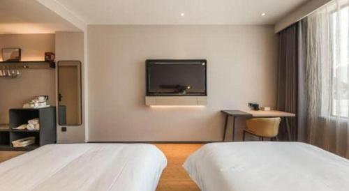 a bedroom with two beds and a tv on the wall at GreenTree Inn Tibet Nyingchi City Biji Shenshan in Nyingchi