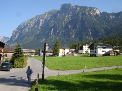a man walking down a road in front of a mountain at Haus Jelini in Schnepfau