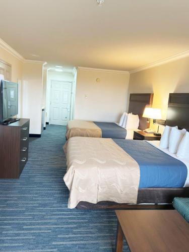 a hotel room with two beds and a flat screen tv at Coratel Inn Ocean Shores Extended Stay in Ocean Shores