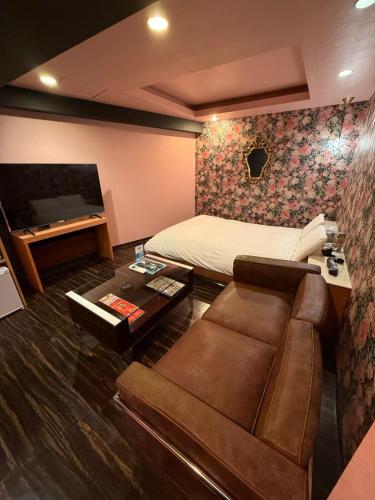 a room with a bed and a couch and a television at Nuda by H-Seven (Adult Only) in Yokohama