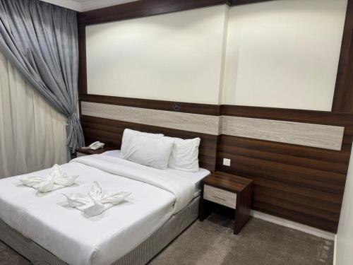 a bedroom with two beds with white flowers on them at فندق شعاع النزهة in Az Zāhir