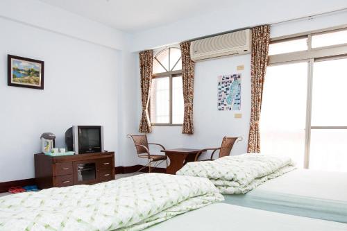 a bedroom with two beds and a tv and a table at 峽谷民宿 Valley B&B in Fushi