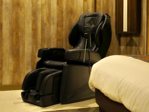 a black recliningining chair next to a bed at HOTEL BOTA 豊橋 -Adult Only- in Toyohashi