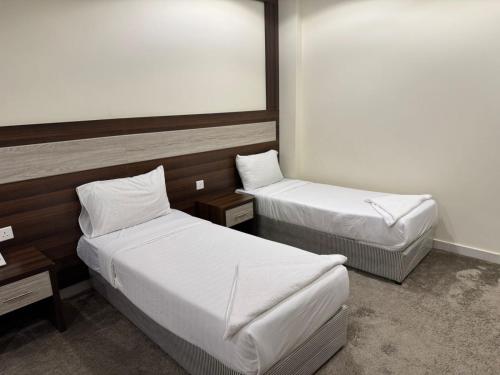 a hotel room with two beds and a table at فندق شعاع النزهة in Az Zāhir