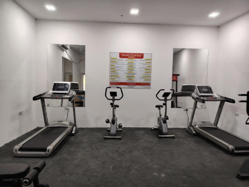 a gym with three treadmills and three machines at Flatjuri in Muscat
