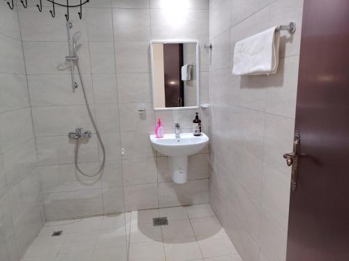 a white bathroom with a sink and a shower at Flatjuri in Muscat