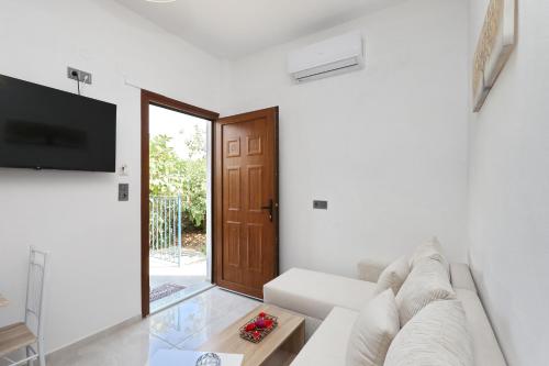 a white living room with a couch and a tv at Smile Stella Studios in Skopelos Town