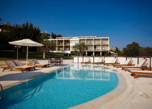 a pool with chairs and an umbrella and a building at Nautica Bay Hotel in Porto Heli
