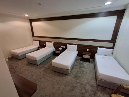 a room with three beds and a large window at فندق شعاع النزهة in Az Zāhir