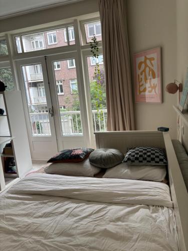a bedroom with a bed with pillows and a window at 185m2 groot appartement met tuin in City Centre in Amsterdam