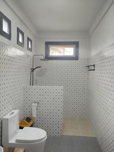a bathroom with a white toilet and a shower at ARISTA Homestay in Tetebatu