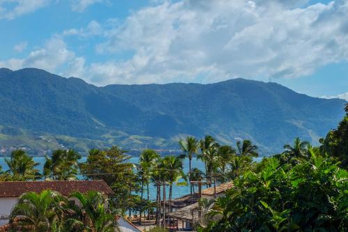 a view of the ocean and mountains with palm trees at Pousada Perequê in Ilhabela