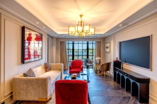 a living room with a tv and a couch and chairs at Fairmont Mumbai in Mumbai