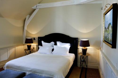 a bedroom with a bed with white sheets and two lamps at La Cour Berbisey - Teritoria in Dijon