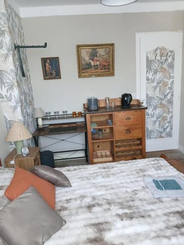 a bedroom with a large bed and a dresser at Chambre " Nid Cosy " Charme et Détente chez Fred in Gorron