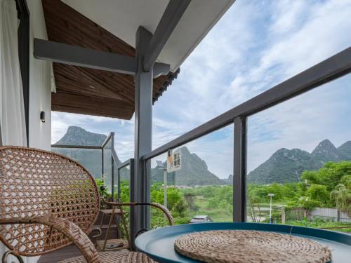 ein Balkon mit Tisch und Stühlen und Bergen in der Unterkunft Guilin Tranquil Peaks Retreat by Reed Flute Cave in Guilin