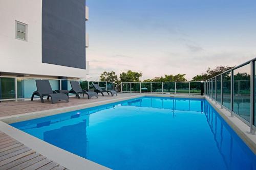 a swimming pool with two chairs next to a building at Marina View Apartment in Townsville