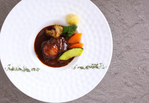 a white plate with food on a table at KAMENOI HOTEL Itako in Itako