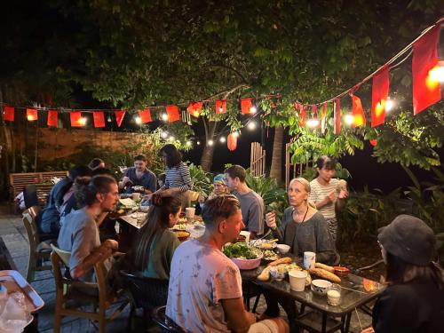 a group of people sitting at a table eating food at Laoxao Lakeview Homestay in Hoi An