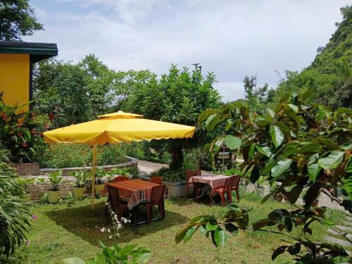 a yellow umbrella and tables and chairs in a yard at Catba Papillon Garden Bungalows & Resort in Cat Ba