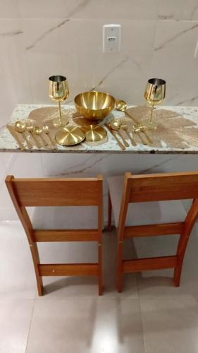 a table with two gold plates and a bowl on it at Lindo apartamento centro barra mansa in Barra Mansa