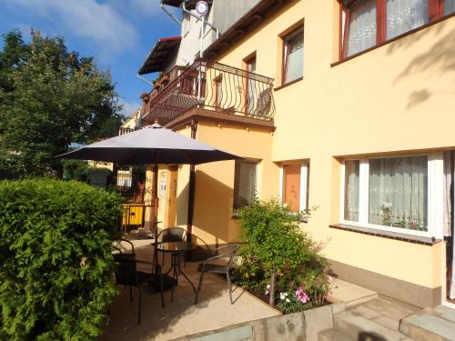 a patio with chairs and an umbrella in front of a building at Apartament CURIE - studio in Międzyzdroje