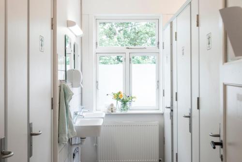 a white bathroom with a sink and a window at Nordliv Strand in Hasle