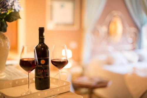 a bottle of wine sitting on a table with two glasses at PALAZZO DEL CAPITANO Wellness & Relais - Luxury Borgo Capitano Collection in San Quirico dʼOrcia