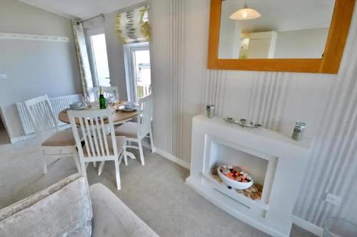 a living room with a fireplace and a dining room table at Stunning Lodge With Decking And Sea-Views In Paignton, Devon Ref 82137W in Paignton