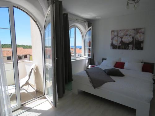 a bedroom with a white bed and a large window at Apartments Villa Urbajs in Vrsar