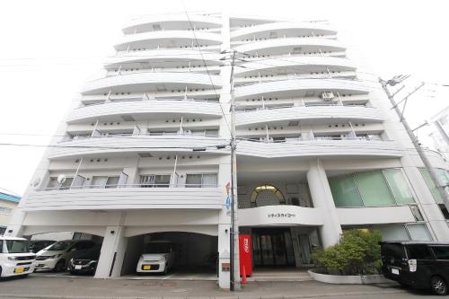 札幌市にあるシティスカイコートの前に車が駐車されている白い建物