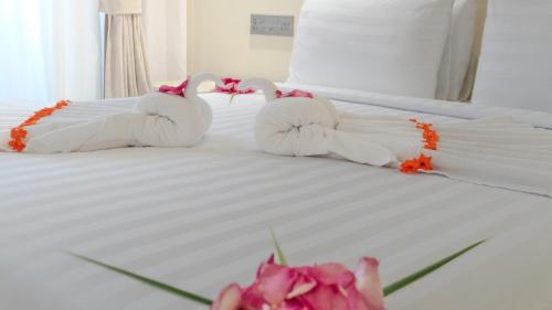 two stuffed swans on a bed with pink flowers at Aquaraa in Maduvvari