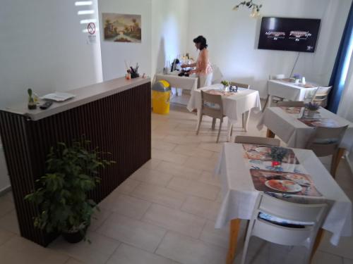 a woman standing in a restaurant with tables and chairs at Prestige Affittacamere Paestum in Stazione di Paestum