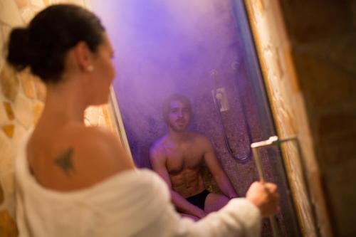 a woman taking a picture of a man in a mirror at PALAZZO DEL CAPITANO Wellness & Relais - Luxury Borgo Capitano Collection in San Quirico dʼOrcia