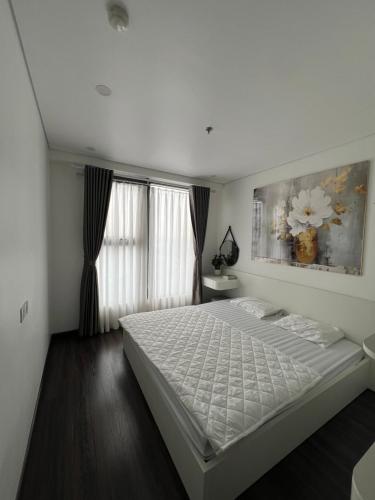 Un dormitorio con una cama blanca y un cuadro en la pared. en Tễu homestay, en Hai Phong