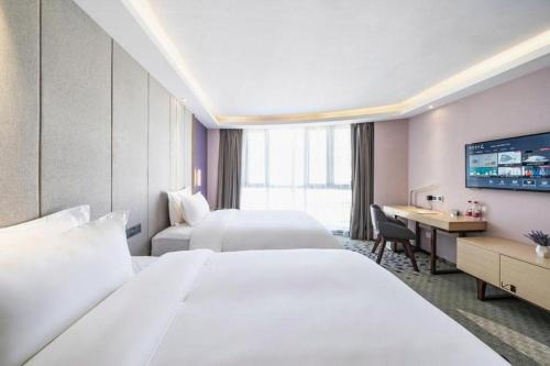 a hotel room with two beds and a desk at Lavande Hotel Jiande Xin'an River in Thousand Island Lake
